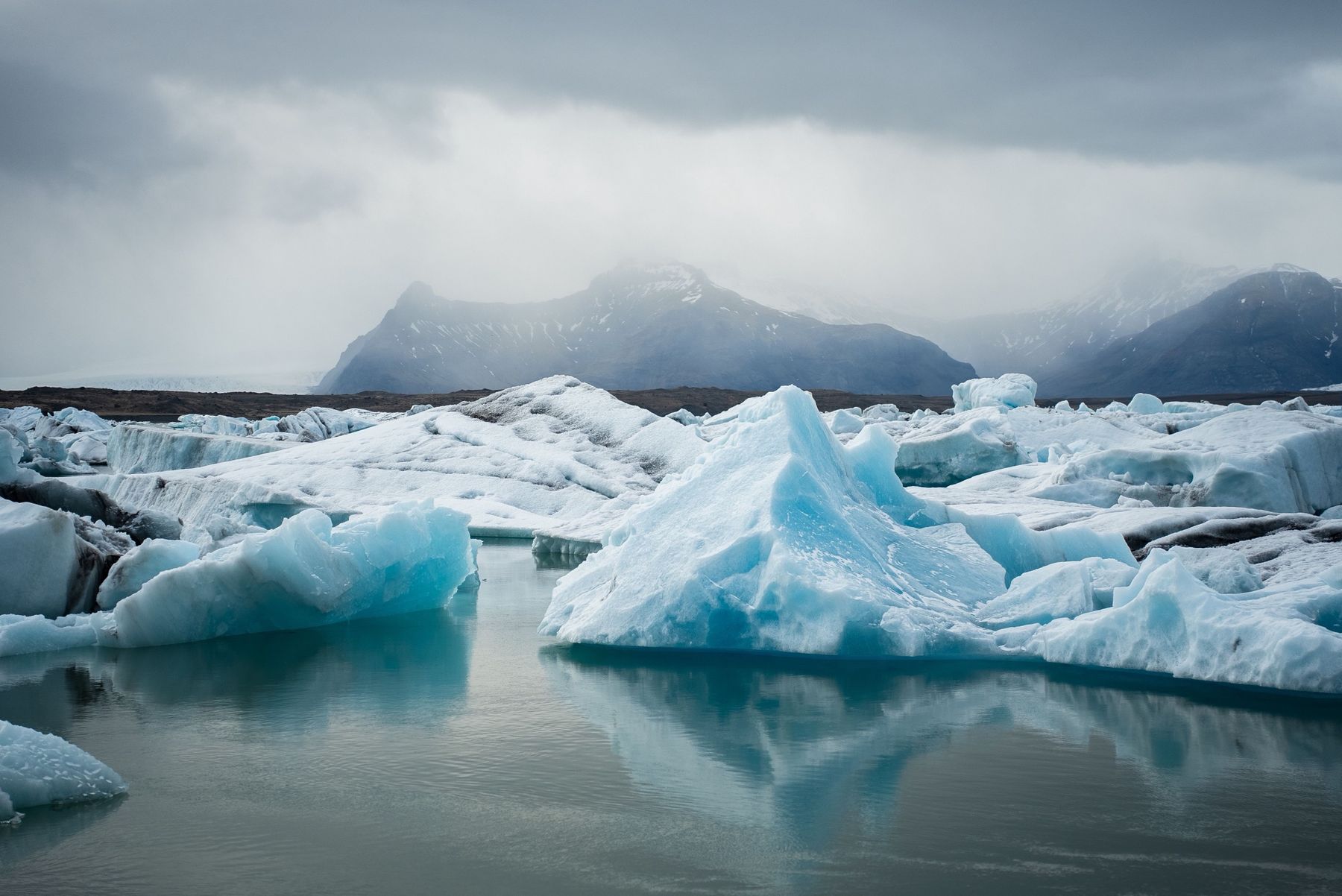 Blue icebergs drifting in a glacier lagoon below misty mountains