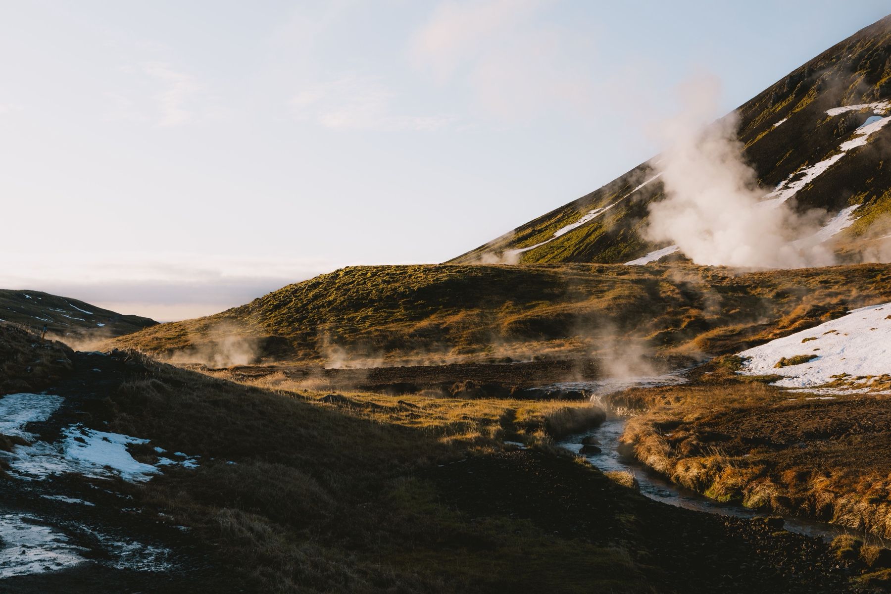 Steam rising from a hot river valley at sunrise, with snow on the hills