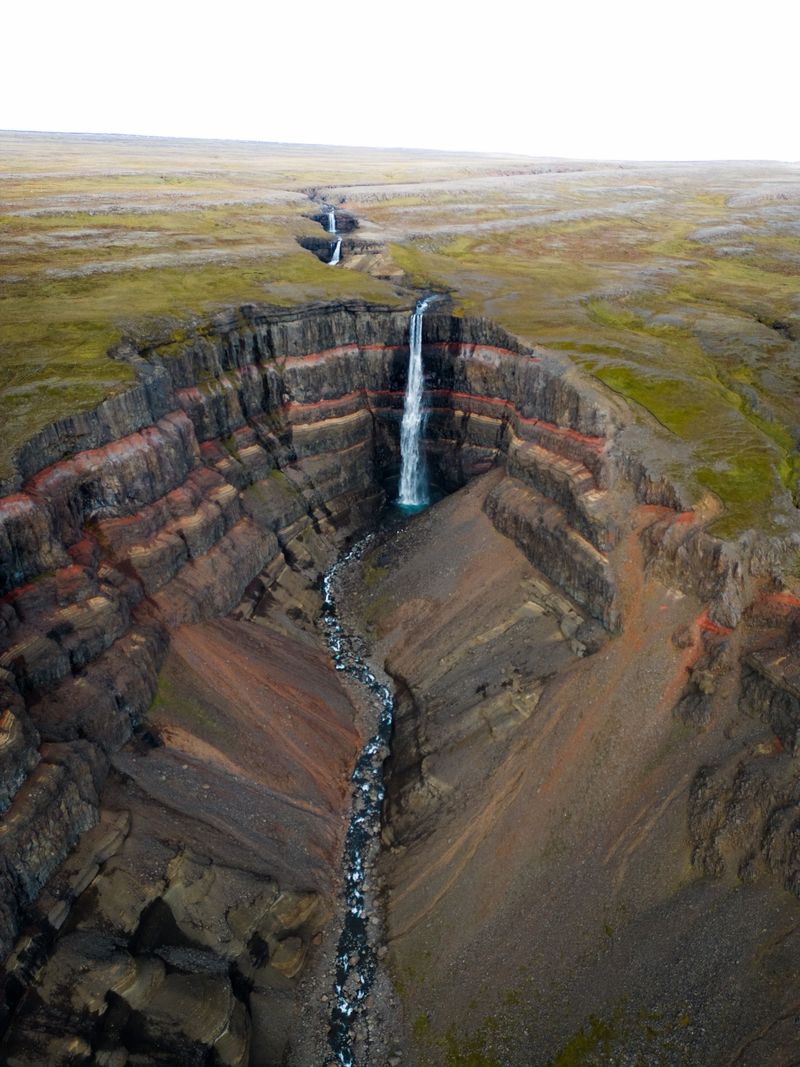 Hengifoss waterfall falling past red and black rock layers