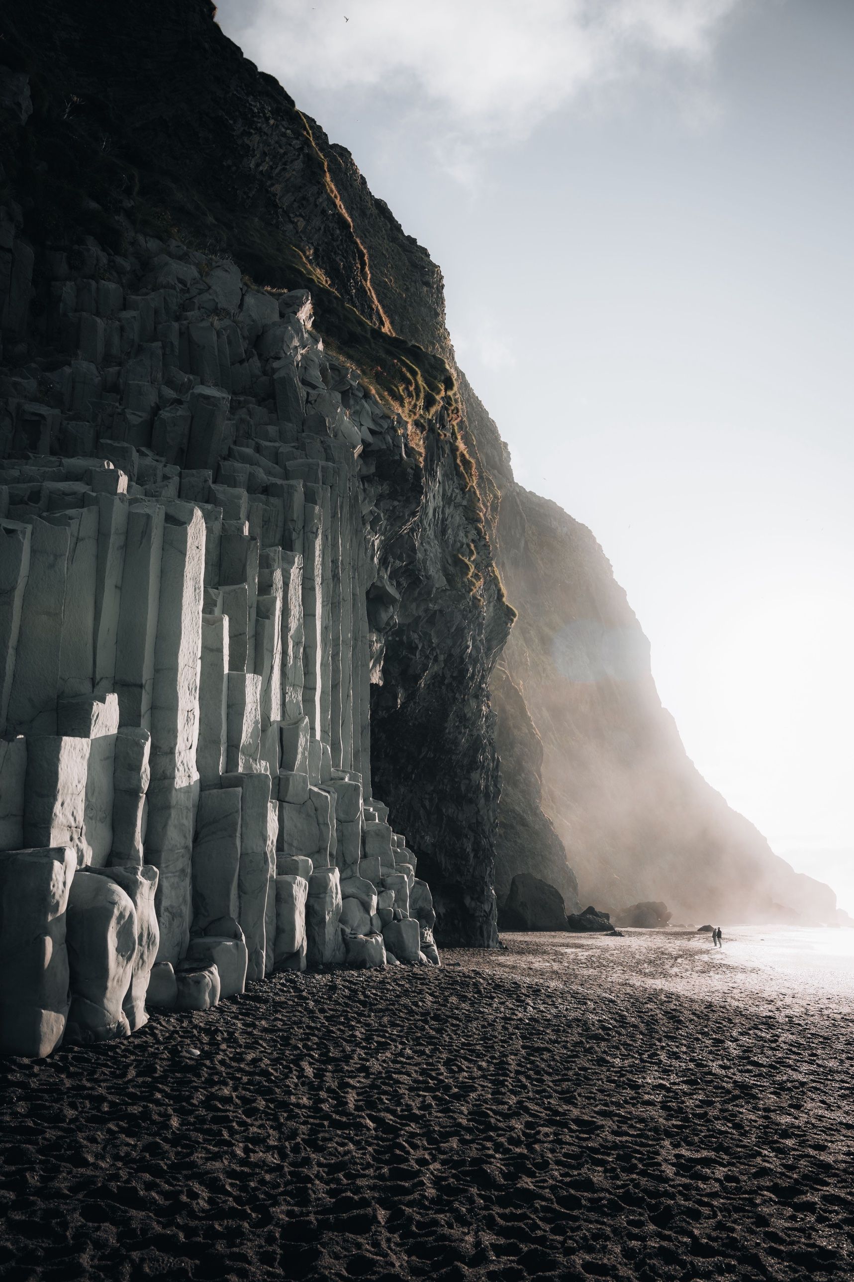 Basalt columns at the foot of a cliff on a black sand beach