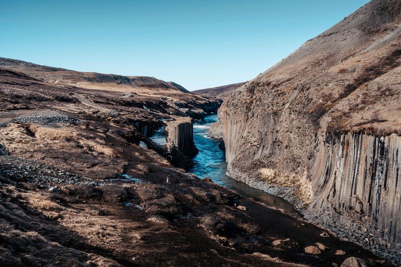 The blue river running through Stuðlagil canyon between basalt columns