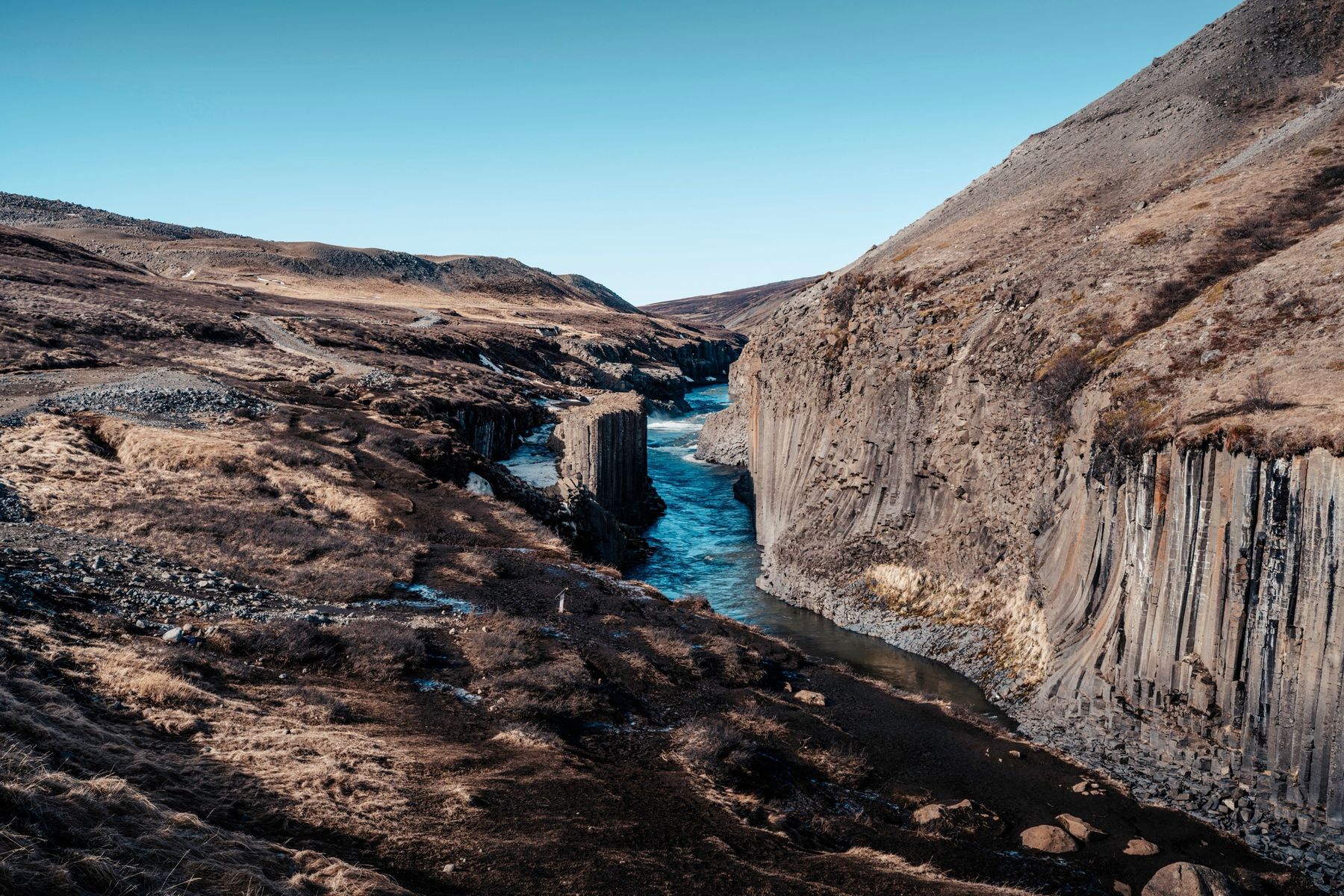 The blue river running through Stuðlagil canyon between walls of basalt columns